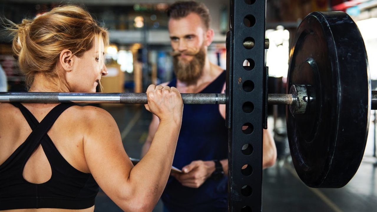 A dedicated tràner guiding a client through a workout session, showcasing motivation and expertise in fitness training.